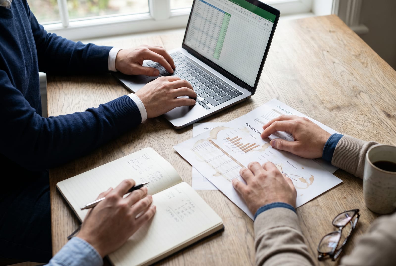 Deux personnes travaillent côte à côte sur un budget : l'une sur un tableur, l'autre annote un graphique financier
