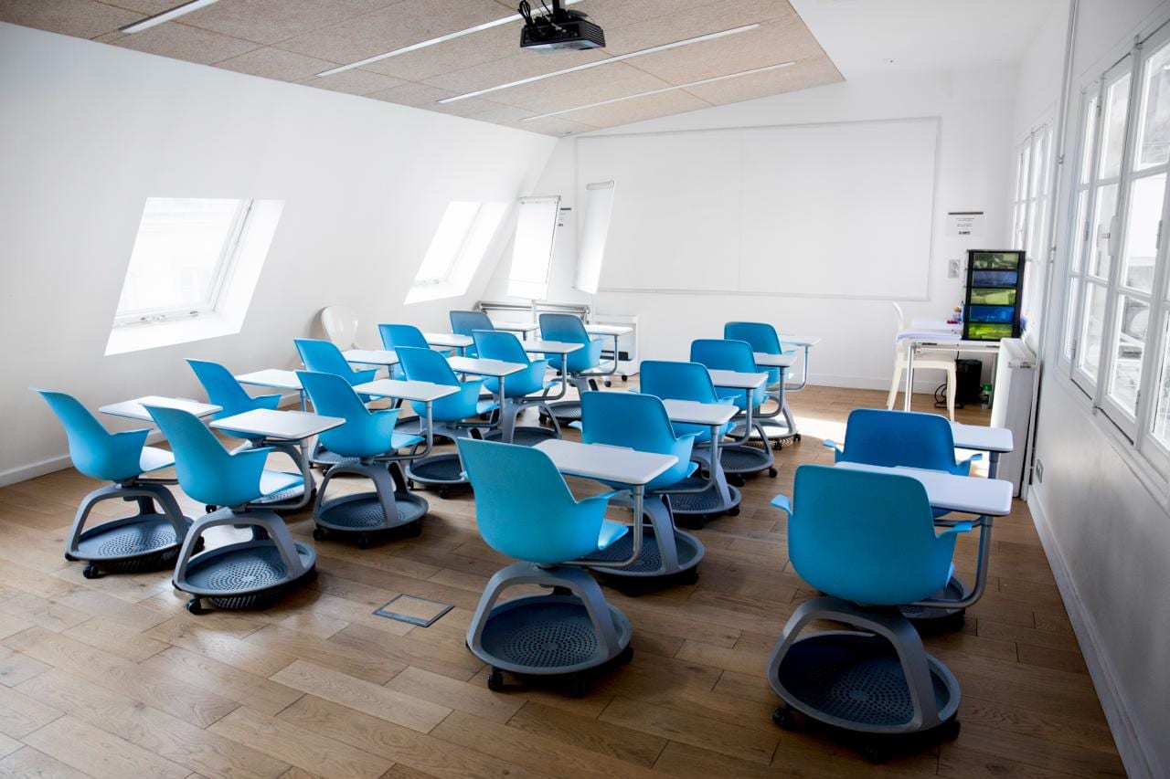 Salle de formation lumineuse équipée de chaises-tablettes mobiles, configurée pour des sessions en petit groupe
